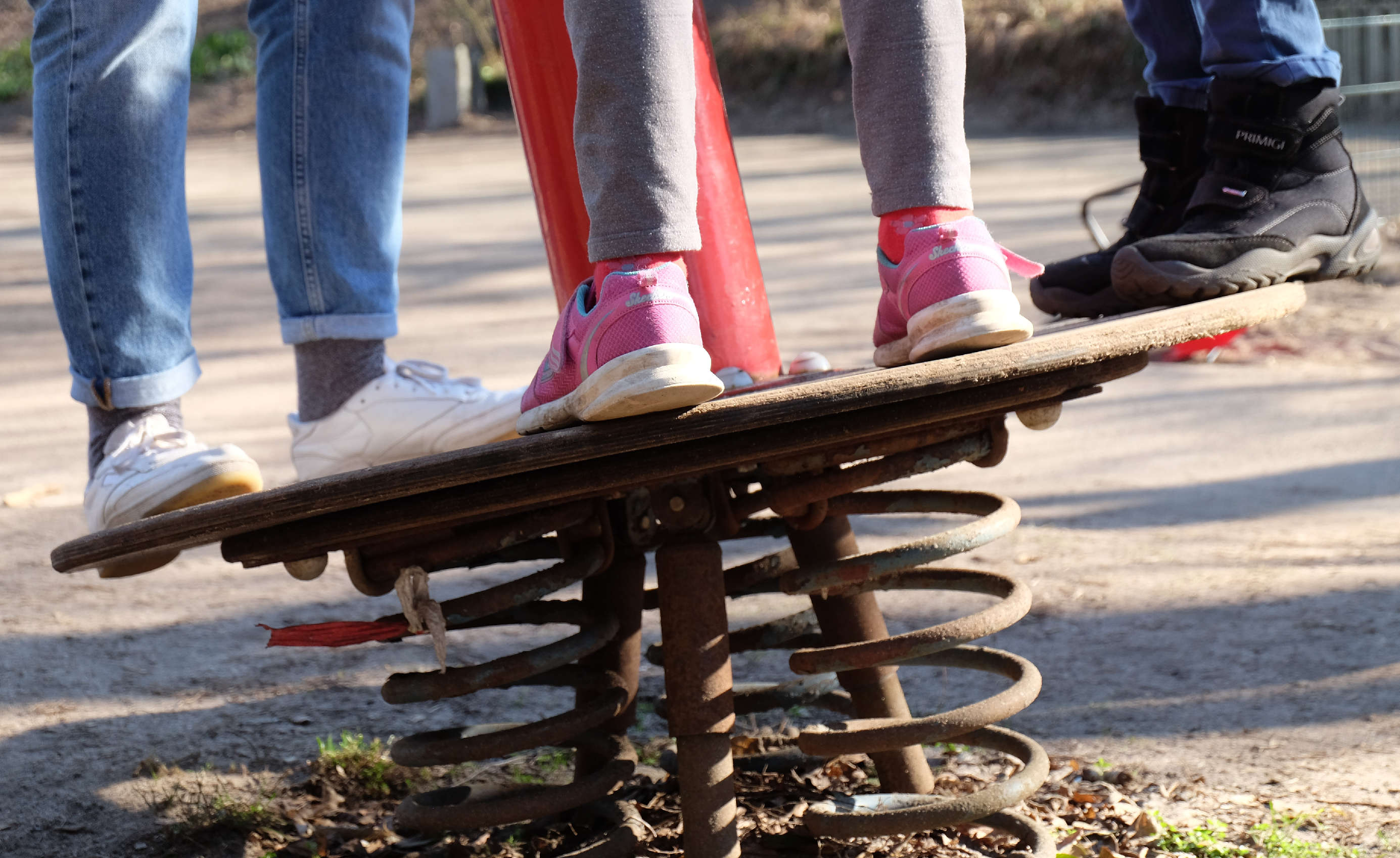 Beine von mehreren Kindern auf einer Wackelplatte auf einem Spielplatz